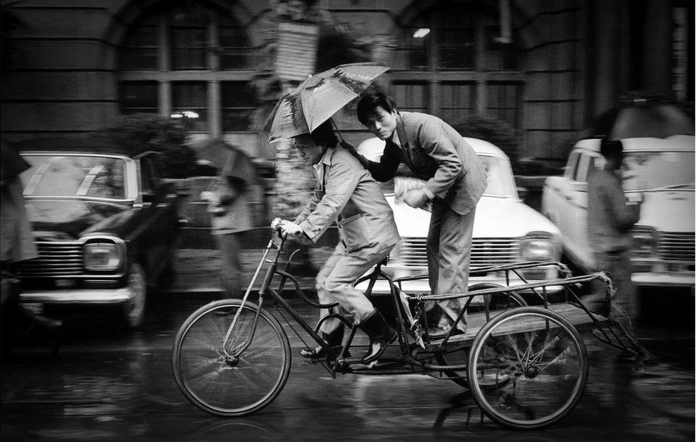 A man stands on a platform attached to a moving bicycle