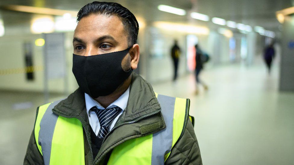 Man waring face covering in high visibility uniform
