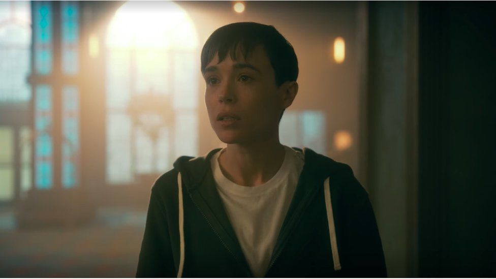 Elliot Page, as his character Viktor in the Umbrella Academy. He has short hair and an open zip-up top.