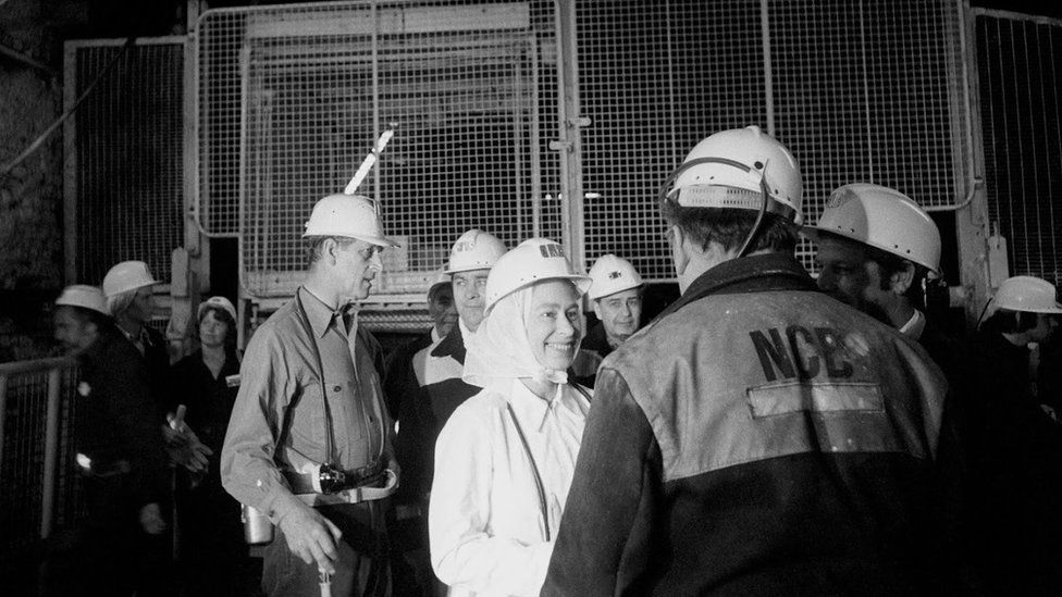 The Queen and Prince Philip in hard hats talking with miners