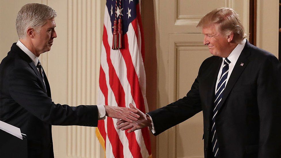 Judge Neil Gorsuch (L) shakes hands with President Donald Trump (R).