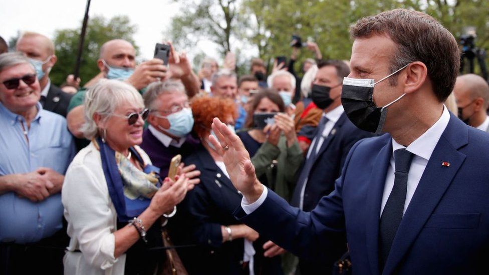 French President Emmanuel Macron (R) greets voters at the polling station in Le Touquet during the first round of the French regional elections