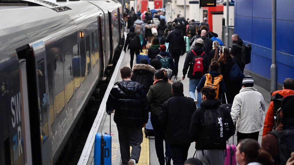 Пассажиры в канун Рождества спешат сесть на поезд на вокзале Ватерлоо в Лондоне
