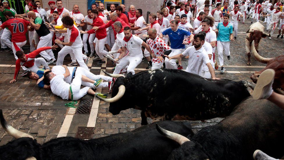 Men cower on the ground away from the bulls in Pamplona 2018
