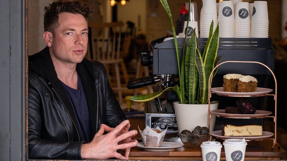 Matt Lanigan sits in his takeaway shop window next to a coffee machine