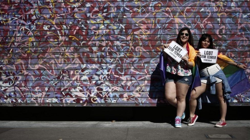 Two women hold signs reading "LGBT without Temer" at the Sao Paulo Gay Pride parade