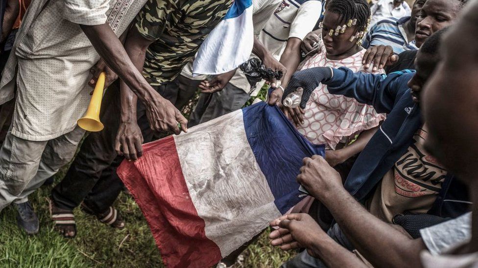 Protesters attempt to burn a French flag in Bamako during a demonstration against French influence in the country