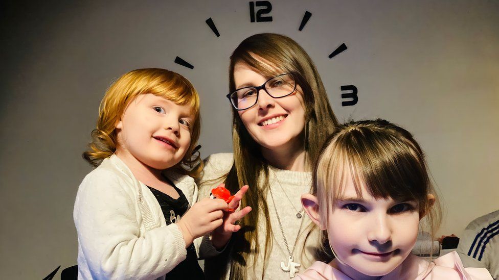 Chelsea and her daughters under a clock