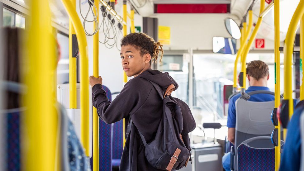 Teenage boy on public transport passenger bus, looking over shoulder.