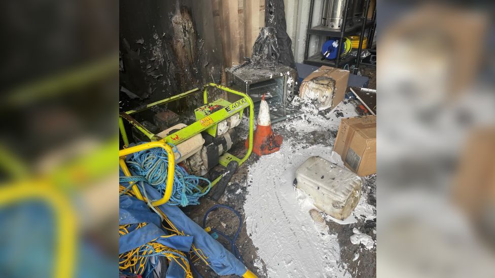 The inside of one storage container, with equipment and tools scattered about the floor. 