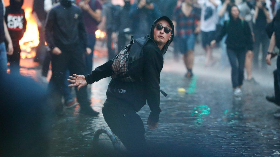 A protester in sunglasses throws stones at riot police on 7 July, 2017 in Hamburg, northern Germany