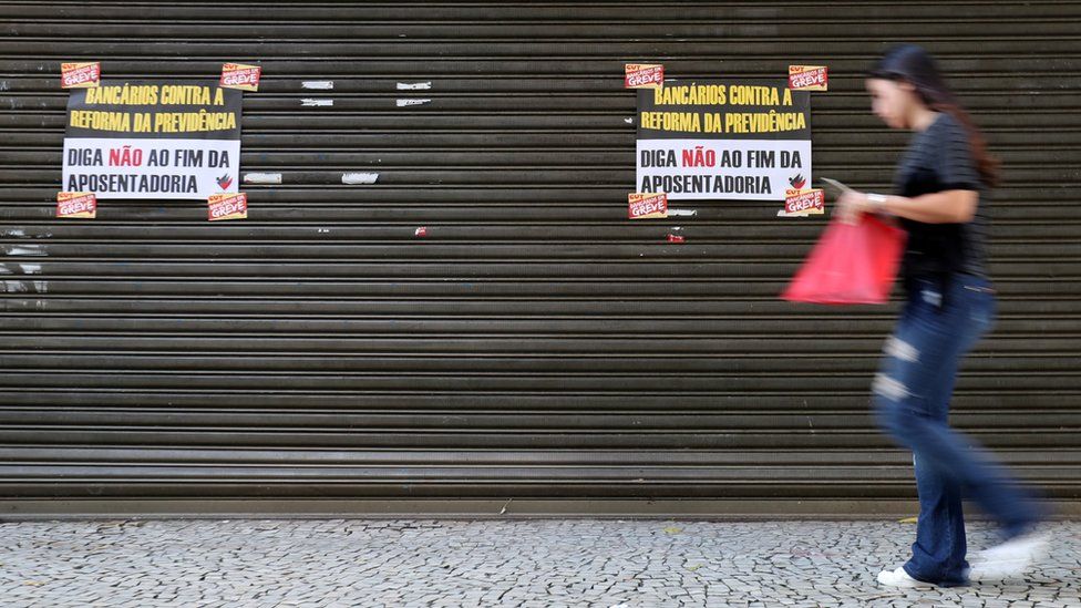 A woman walks past a bank during a general strike against the government's pension plan in Rio de Janeiro