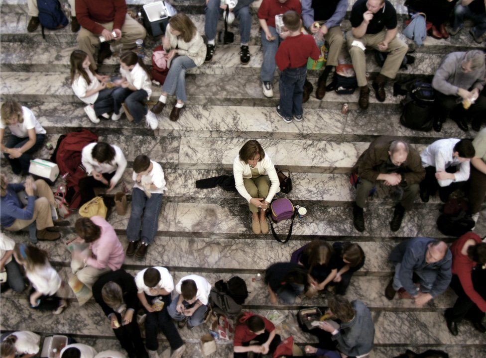 A woman sits alone on crowded steps