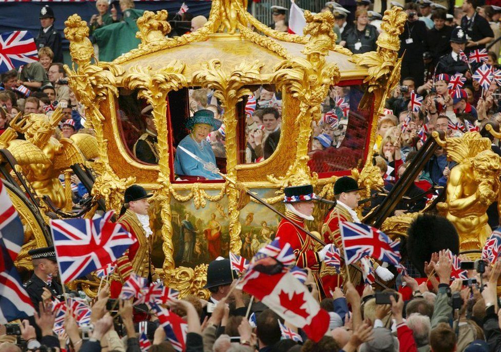 Britain's Queen Elizabeth and Prince Philip ride in the Golden State Carriage at the head of a parade from Buckingham Palace to St Paul's Cathedral celebrating the Queen's Golden Jubilee, on 4 June 2002, along The Mall in London.