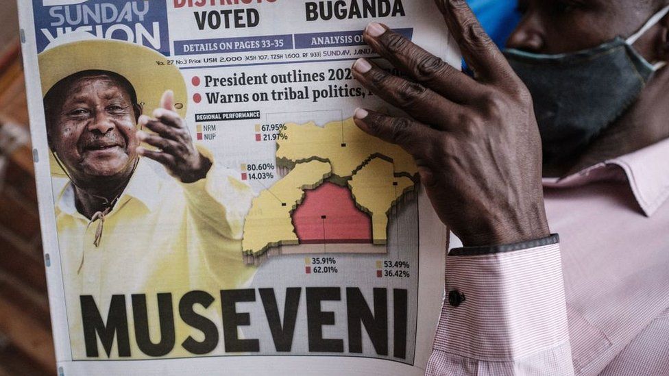 A man reads the "Sunday Vision" newspaper whose front page shows a portrait of re-elected President Yoweri Museveni on January 17, 2021 at a kiosk on a street in Kampala
