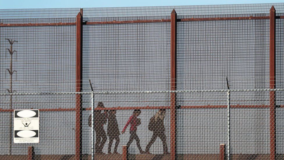 Migrants walk together along the US-Mexico border wall near El Paso on 4 June 2019