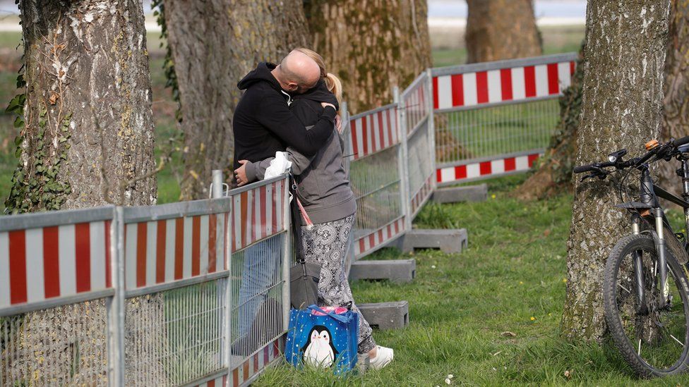 A couple hug as they stand on both sides of a fence built by German authorities on the German-Swiss border on 20 March