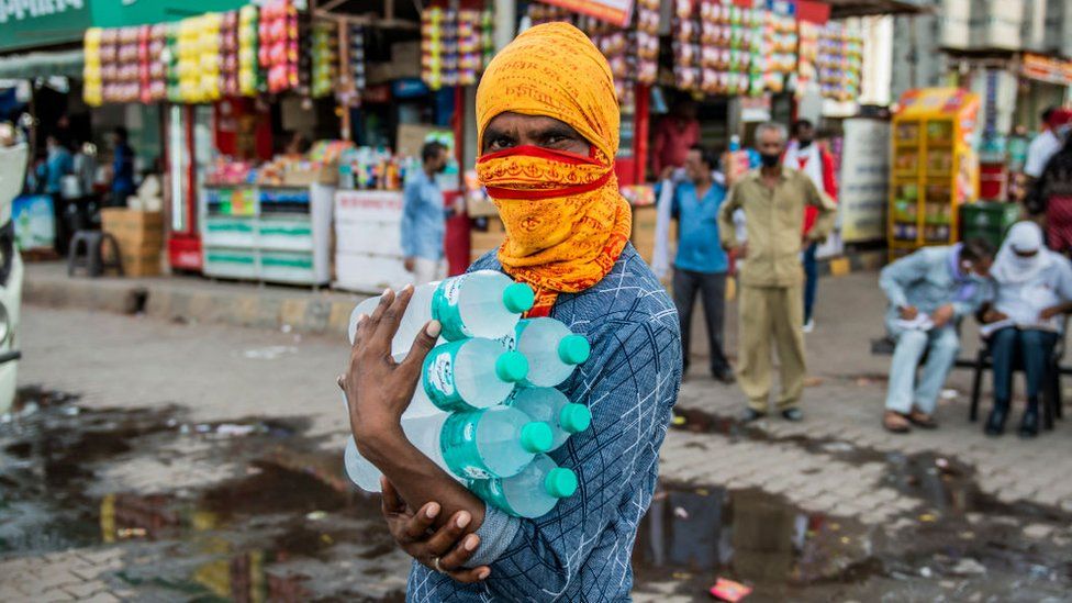 A vendor carries bottles of mineral water at a bus depot in Uttar Pradesh.