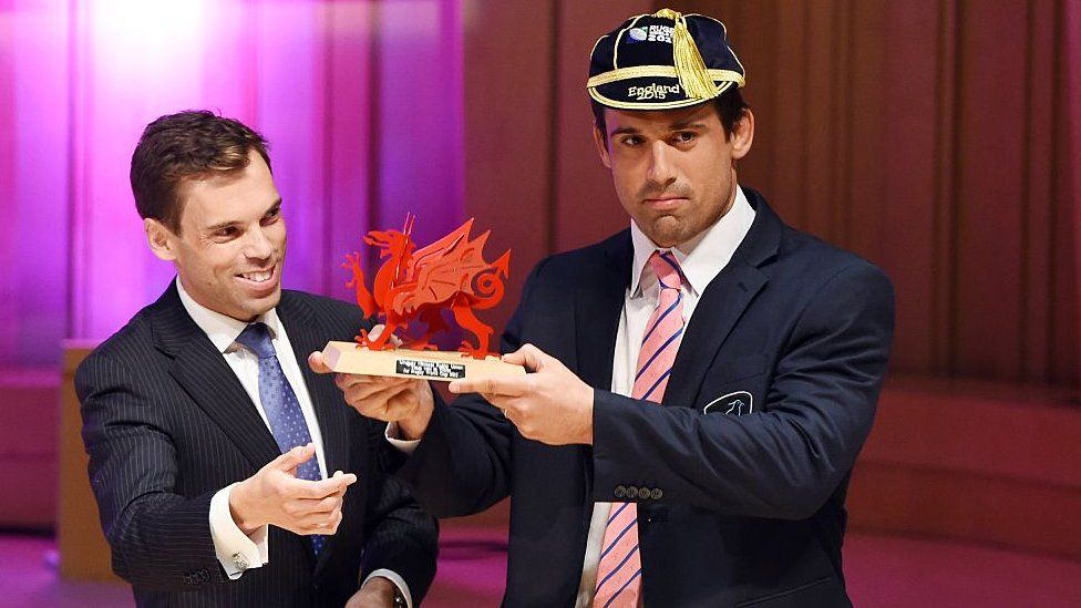 Ken Skates on stage giving a Welsh dragon to Uruguay's captain Santiago Vilaseca
