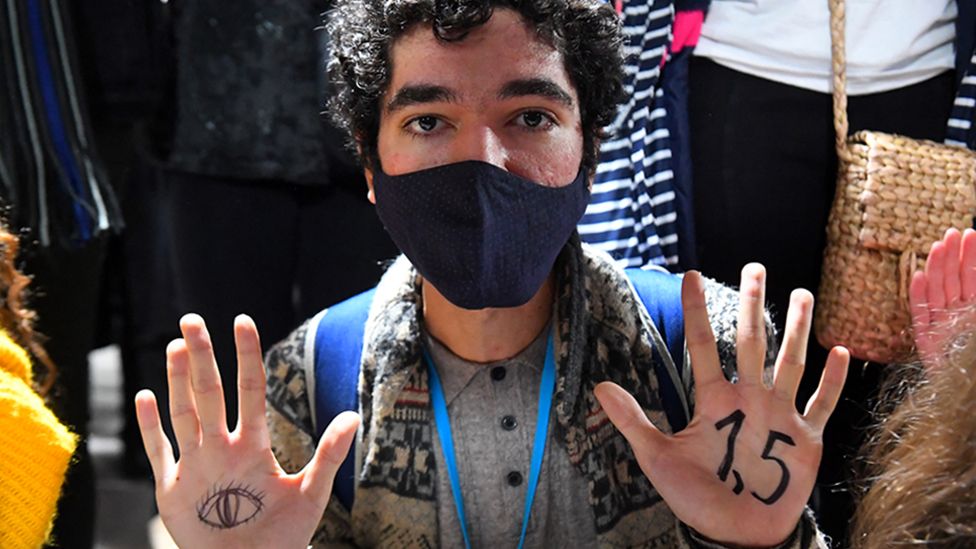 A youth climate activist in Glasgow shows 1.5 and eye drawn on his hands. Photo: 10 November 2021