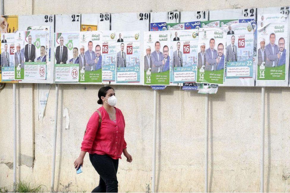 A woman walks past the political adverts in Algers, Algeria, on 8 June.