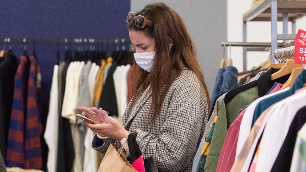 A woman checks her phone while shopping