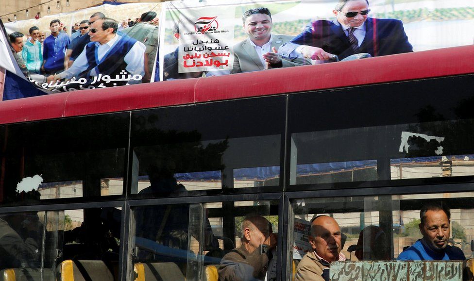 People look out of a bus window in front of posters of Egypt"s President Abdel Fattah al-Sisi for the upcoming presidential election in Cairo, Egypt February 28, 2018