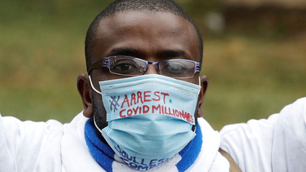 Кенийский мужчина в маске с надписью «арестовать миллионеров Covid» - август 2020 г.