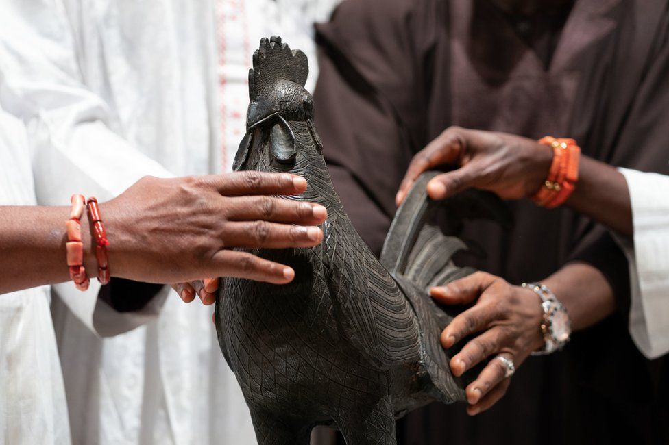 Nigerian officials get their hands on the bronze rooster.