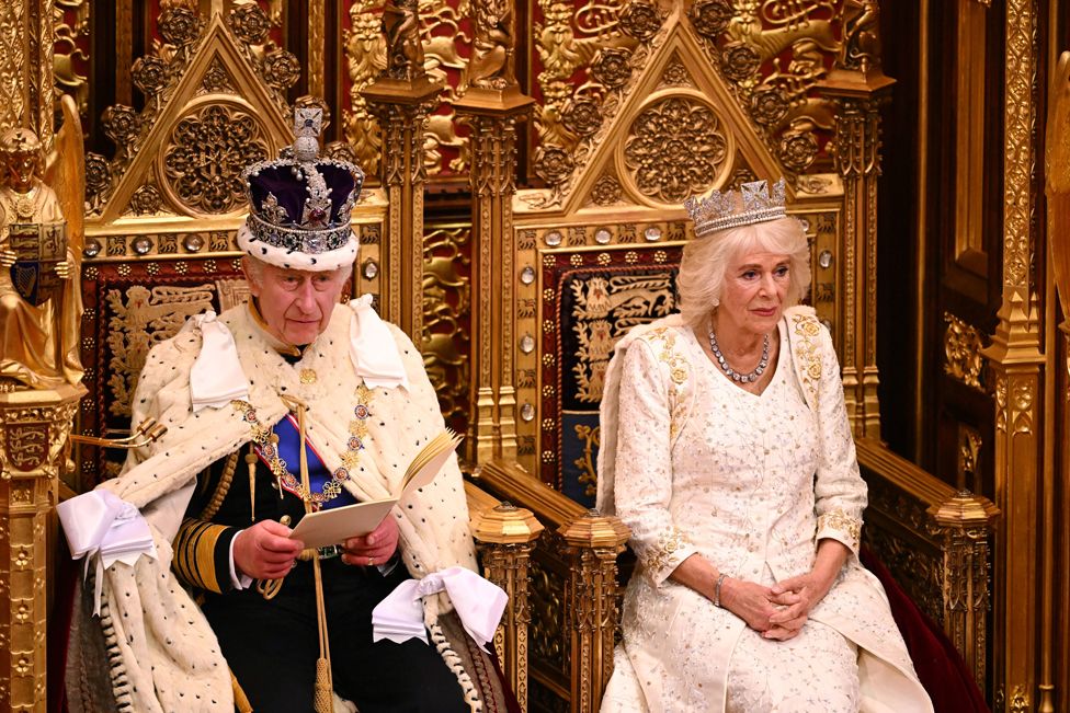 King Charles III delivers a speech beside Queen Camilla during the State Opening of Parliament in the House of Lords at the Palace of Westminster in London