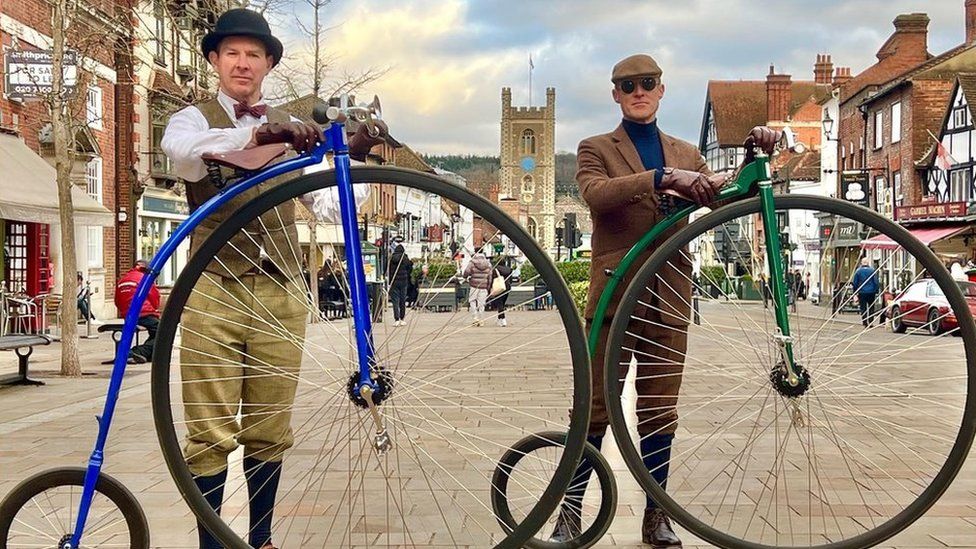 two men standing by penny farthings