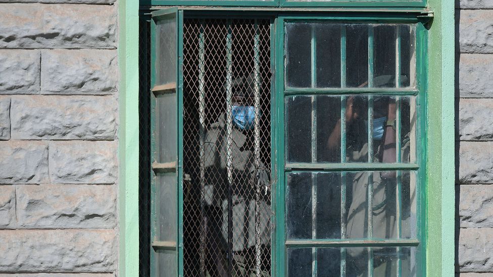 Wardens seen through a barred window at Kamiti Maximum Prison in Kenya, 2021