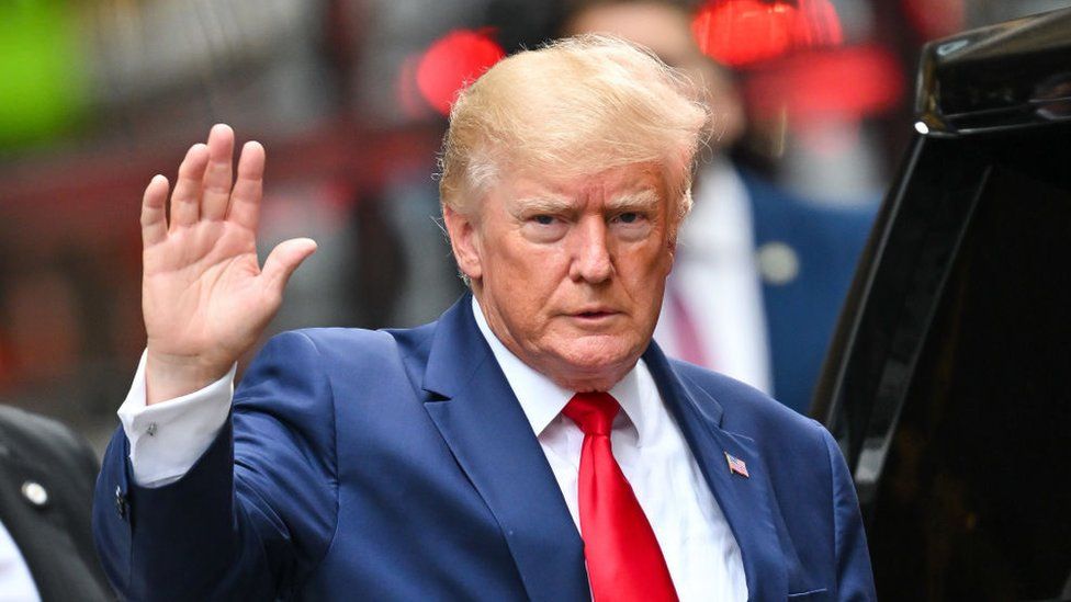 Donald Trump waves as he leaves Trump Tower in August 2022