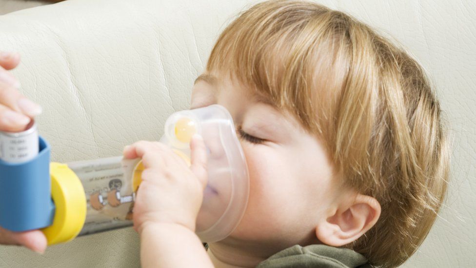 file picture of child with asthma inhaler and spacer device