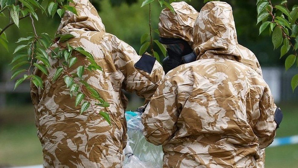 People in military hazardous material protective suits collect an item in Queen Elizabeth Gardens in Salisbury