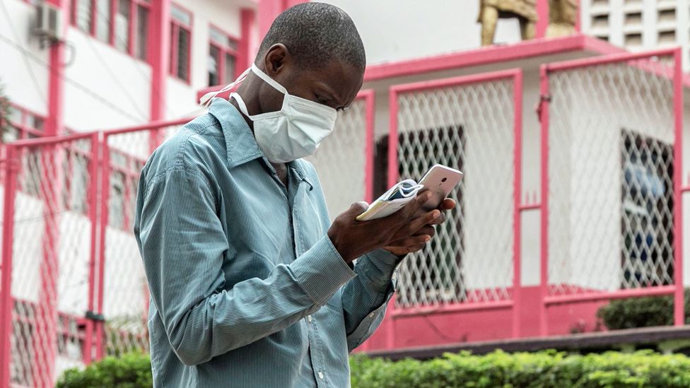 A man in a facemask looking at his phone in Yaoundé, Cameroon - Friday 6 March 2020