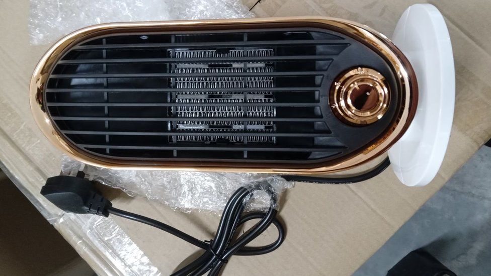 A small desk top heater. It has a black grill, white base and rose gold trim