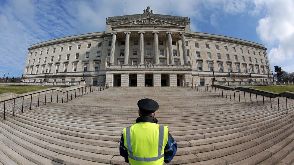 A security guard stands on the steps of Stormont's Parliament Buildings
