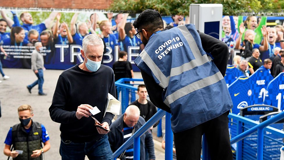 A Chelsea fan shows vaccine related paperwork to a covid-19 steward outside the stadium before the match - 25 September 2021