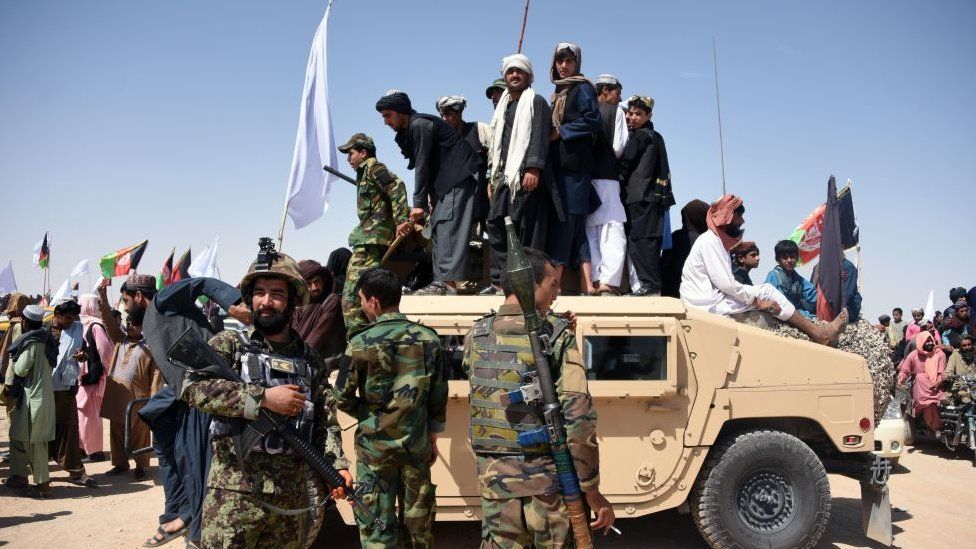 Afghan Taliban militants and residents stand on a armoured Humvee vehicle of the Afghan National Army as they celebrate a ceasefire on the third day of Eid in Maiwand district of Kandahar province