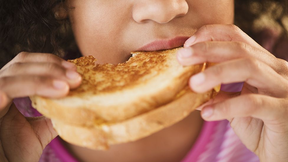 Close up of a child eating a sandwich