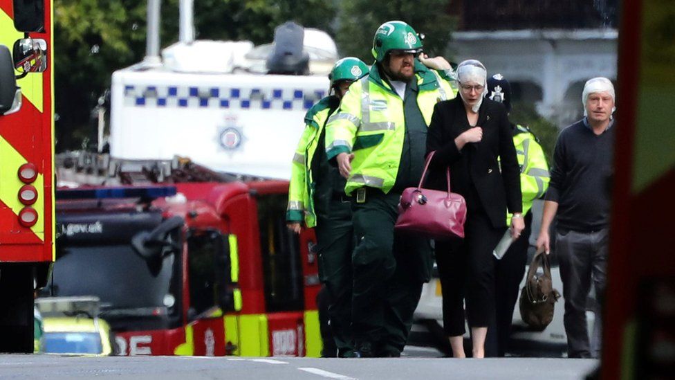 Paramedics lead a woman away from the scene