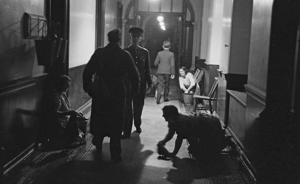Cleaners at work in the early morning in a corridor at the War Office, Whitehall, London, December 1940
