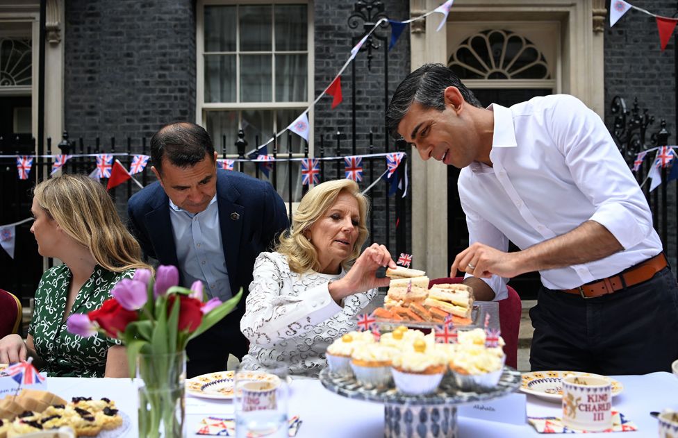 British Prime Minister Rishi Sunak (R) offers US First Lady Jill Biden a sandwich during a coronation big lunch for community heroes, Ukraine refugees, and youth groups at 10 Downing Street in London, Britain, 07 May 2023, following the coronation of Britain's King Charles III at Westminster Abbey in London on 06 May.