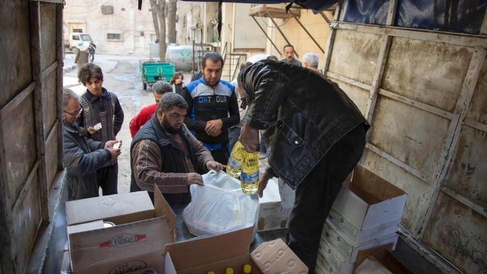 Syrian families receive aid packages by Al-Sham Humanitarian Foundation in the rebel-held neighbourhood of al-Marjah in the northern city of Aleppo (15 November 2016)