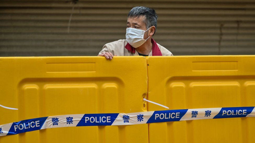Мужчина стоит за барьерами во время блокировки в качестве меры против коронавируса Covid-19 в Шанхае.