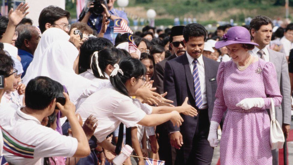 British Royal Queen Elizabeth II, wearing a lavender print dress with a wide-brim lavender hat, in Malaysia, October 1989.