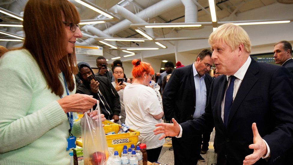 Prime minister Boris Johnson speaks to a helper