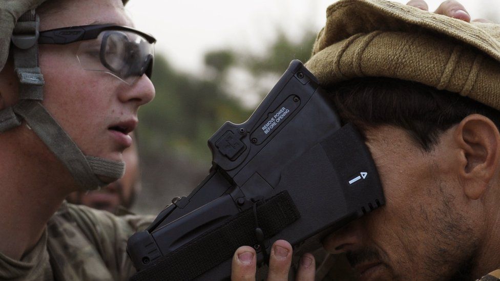 A US solider collects biometric information from a villager