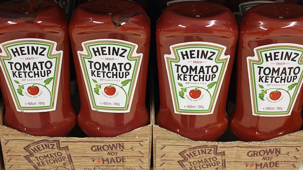 Bottles of Heinz Tomato Ketchup on a shop shelf.